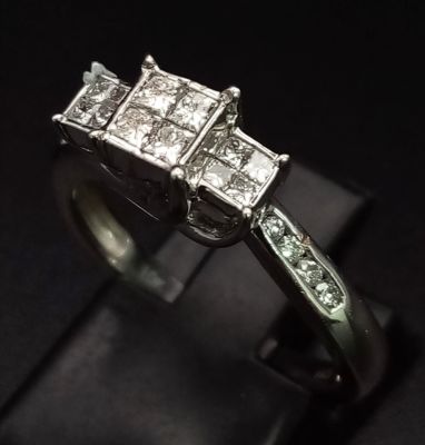 A 10K White Gold Diamond Ring. Three squares of Princess-cut diamonds supported by round-cut 