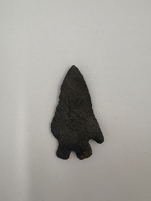 Kirk - 2in. Dark gray to black stone projectile point with a narrow triangular blade and 