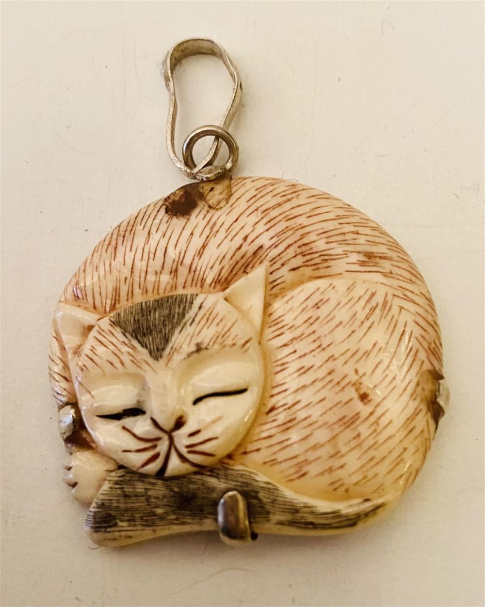 Lot 449: Bone sleeping cat pendant