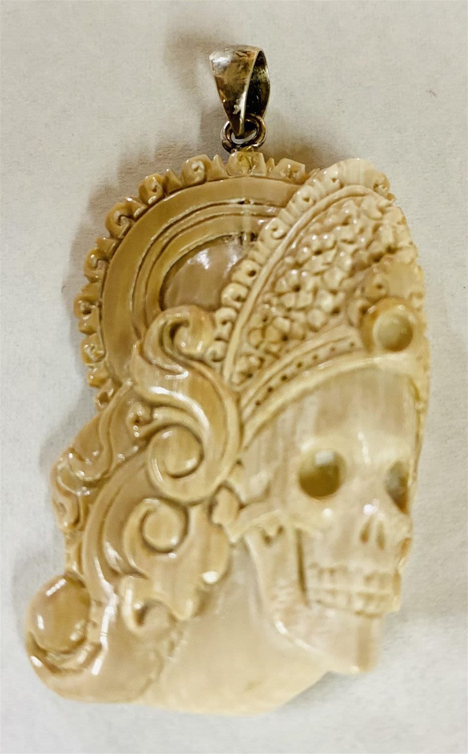 Lot 366: Carved bone pendant skeleton face-