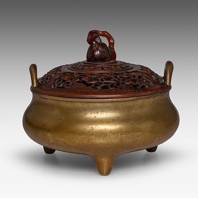 A Chinese bronze tripod censer, paired with upright loop handles and matched with a carved 