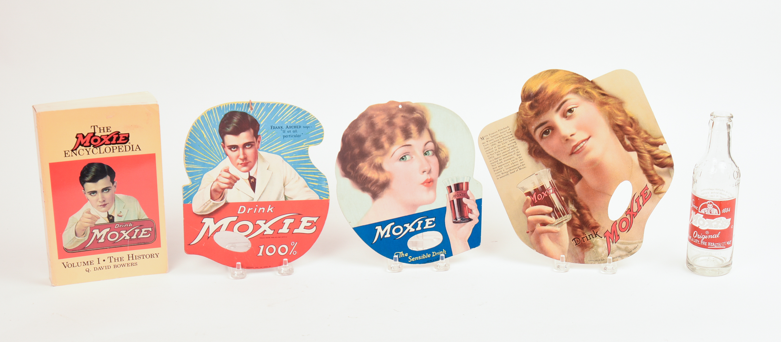 Three Moxie Hand Fans, The Moxie Encyclopedia, and a Moxie Botttle.