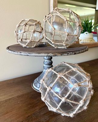 A Metal Cake Stand with Three Decorative Nautical-Style Glass Balls in Netting. This lot 