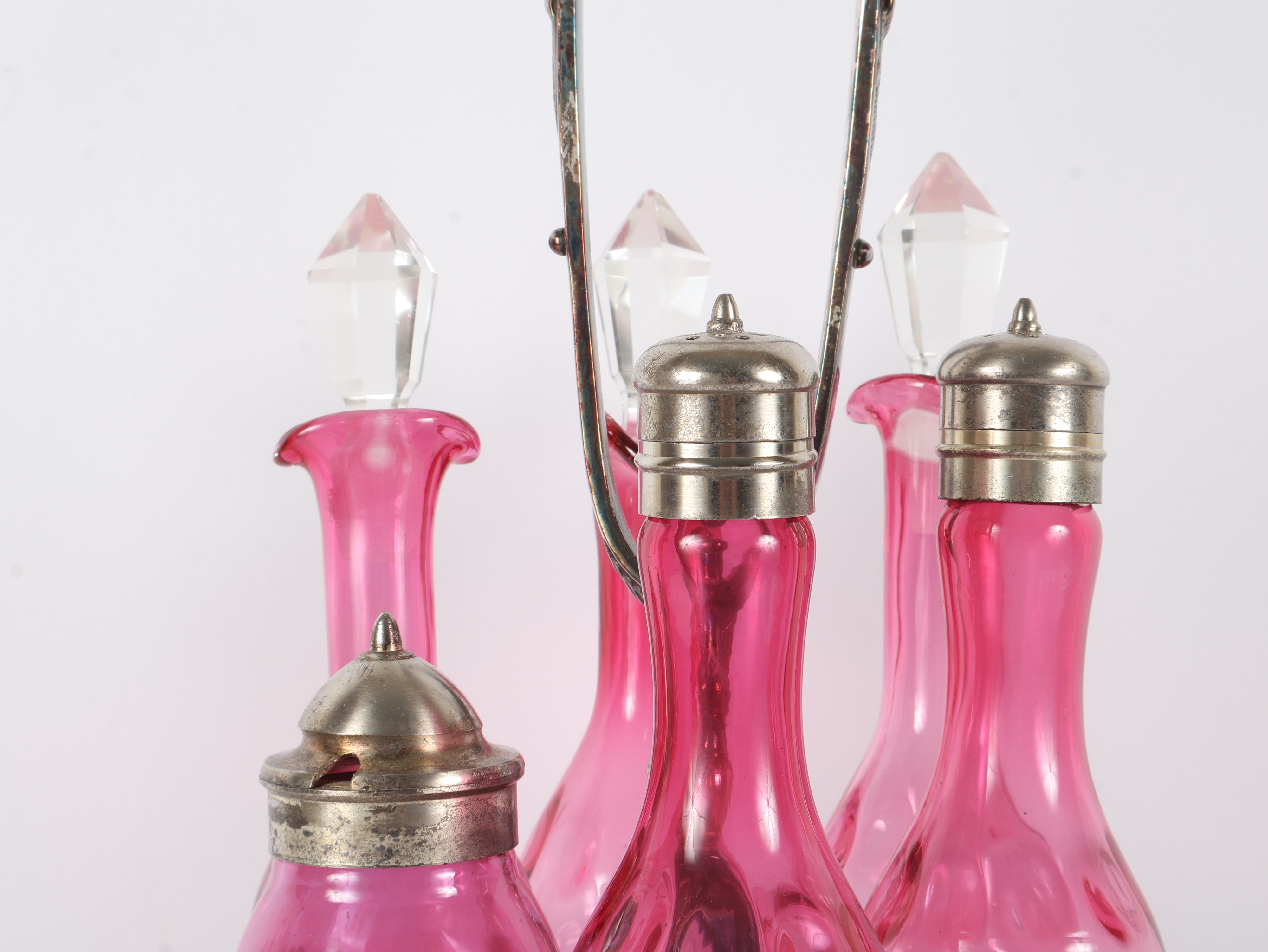 A Set of Five Victorian Cranberry Glass Bottles in an Ornate Silver-Plated Caster Stand