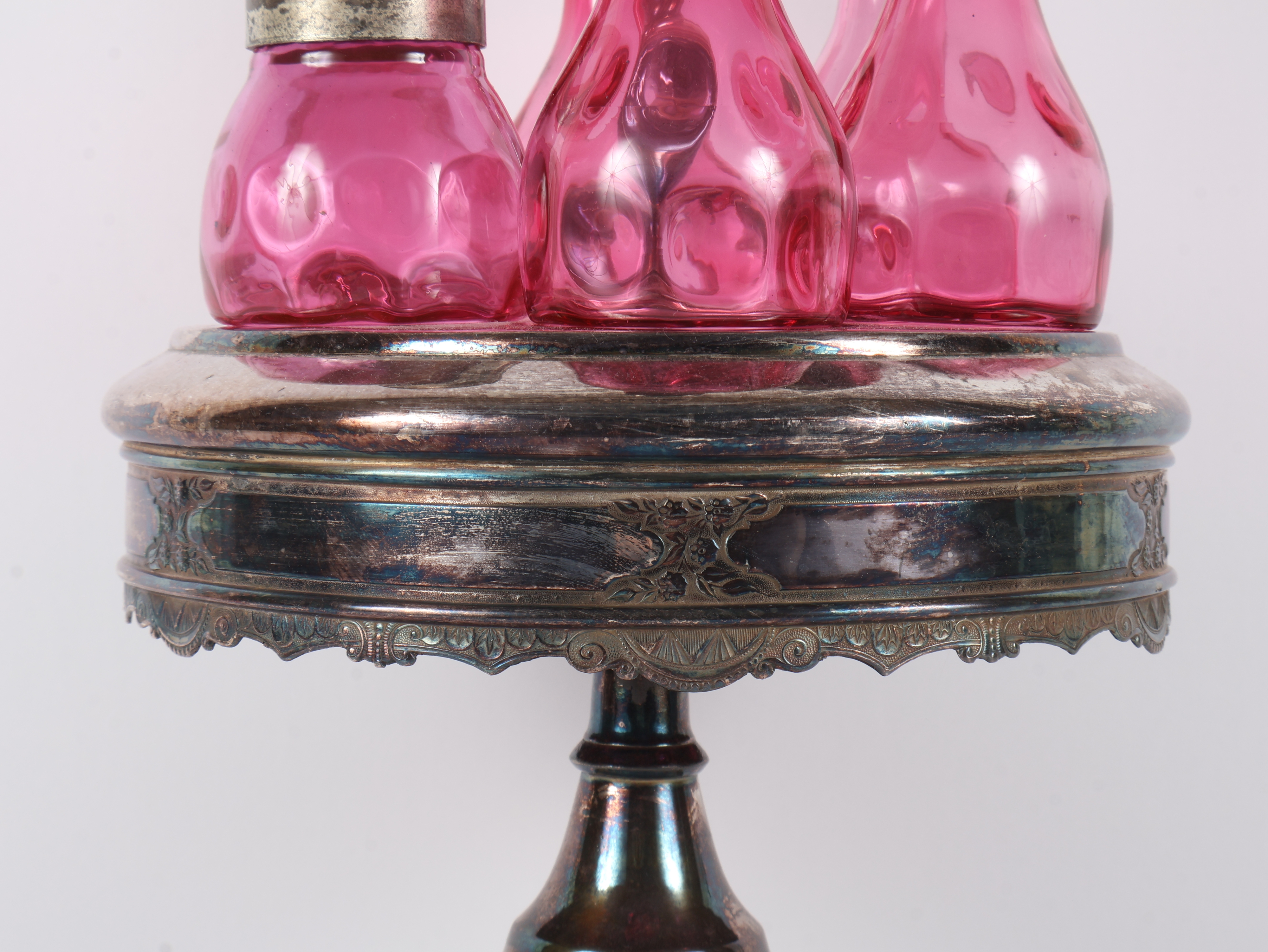 A Set of Five Victorian Cranberry Glass Bottles in an Ornate Silver-Plated Caster Stand