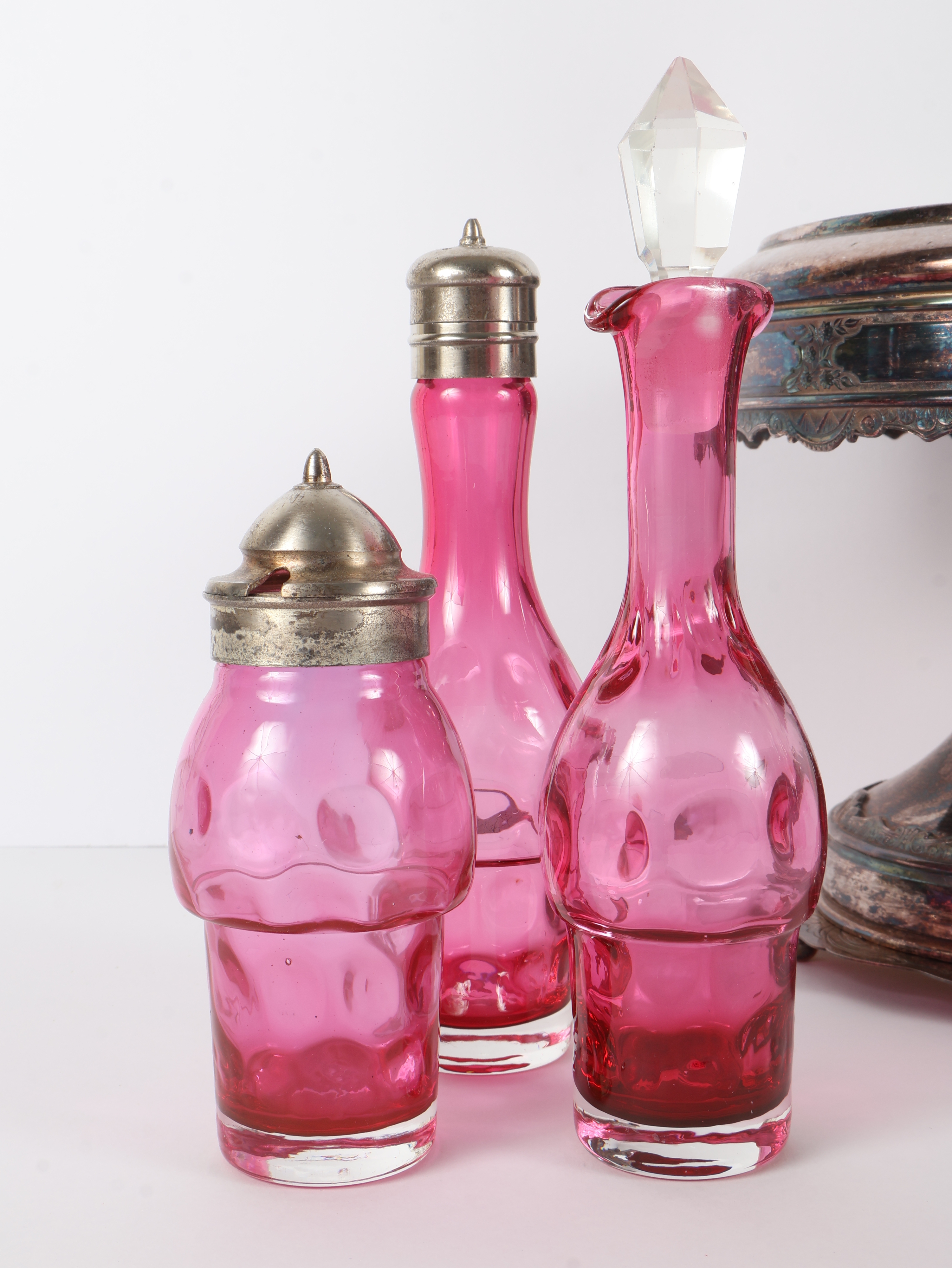 A Set of Five Victorian Cranberry Glass Bottles in an Ornate Silver-Plated Caster Stand