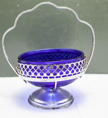 קערת זכוכית בצבע כחול קובלט עמוק המונח בתוך מעמד מתכת כסוף