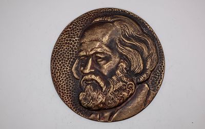 יצירת מתכת אמנותית עם עבודת תבליט מפורטת של מארקס על רקע מרקם נקודתי (Pebbled) בגוון ברונזה עתיק