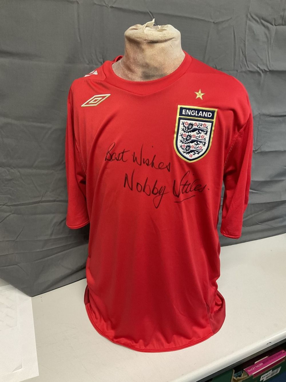 Lot 179: Football Nobby Stiles signed England replica red away...