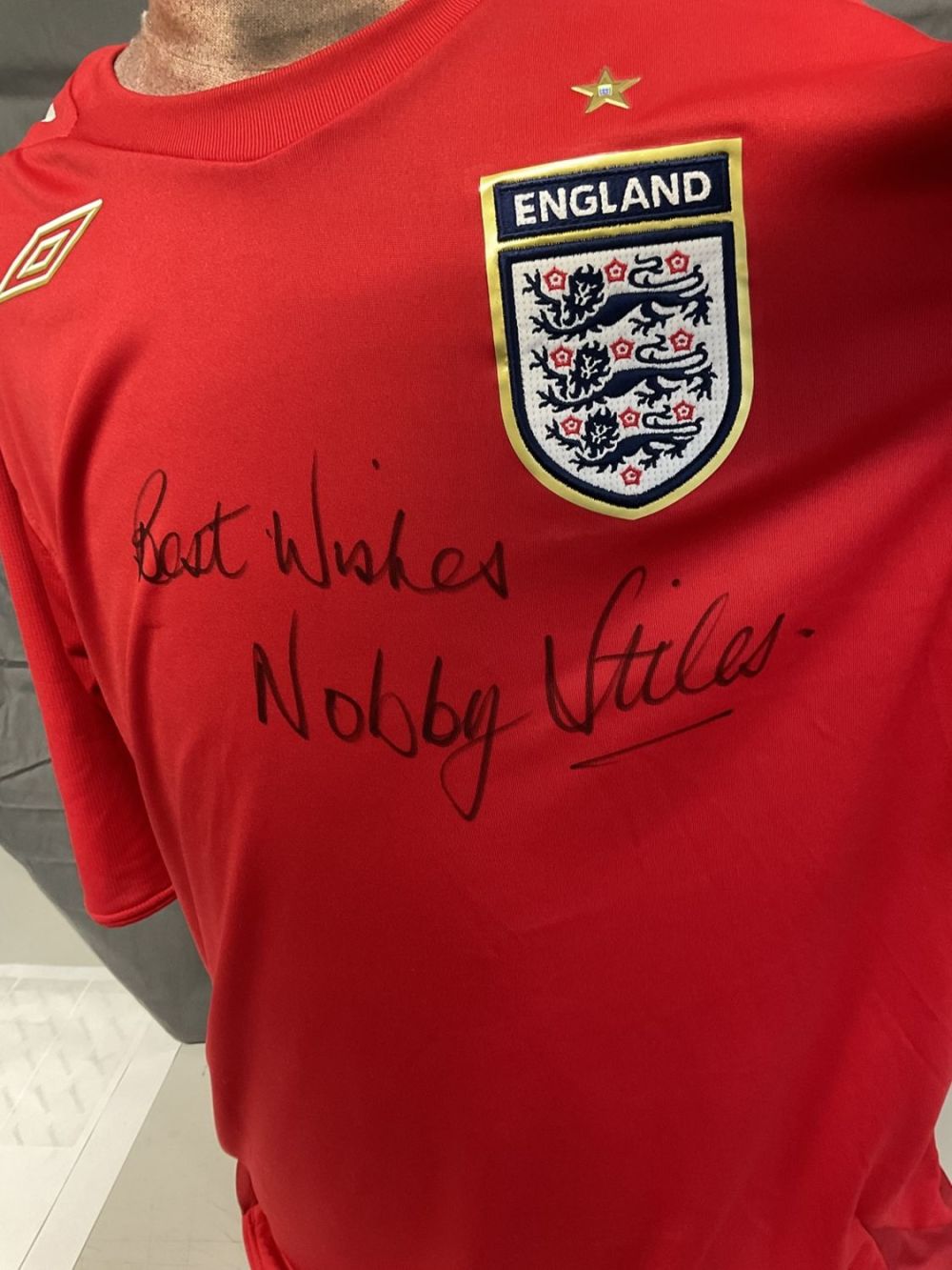 Lot 210: Football Nobby Stiles signed England replica red away...
