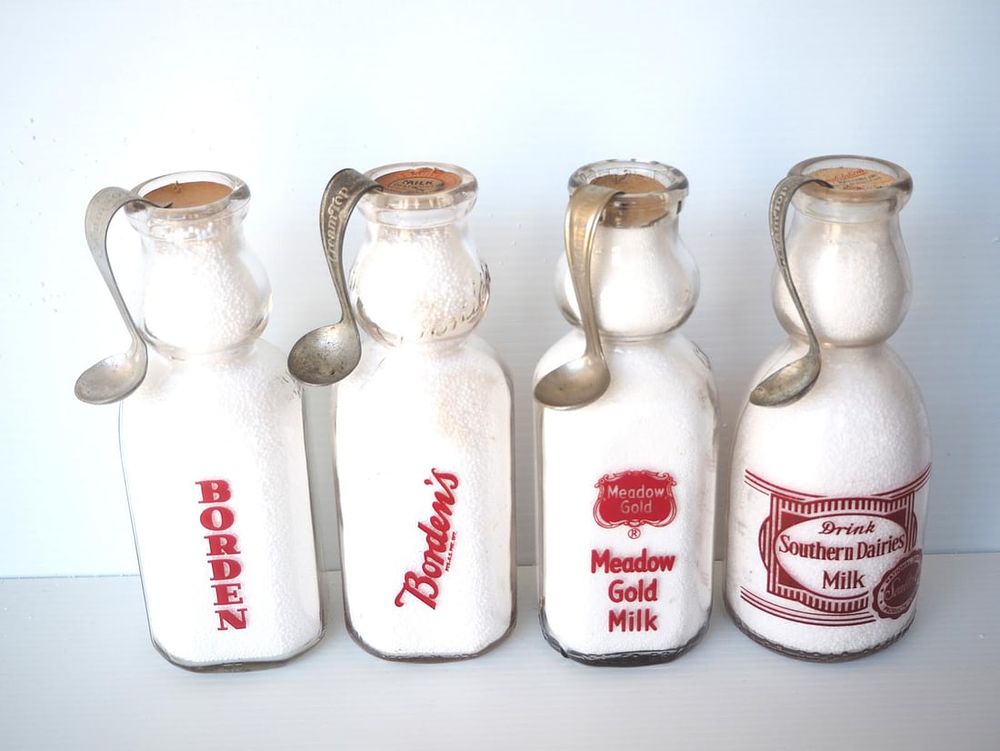 Lot 654: (4) 1 quart cream top milk bottles with spoons