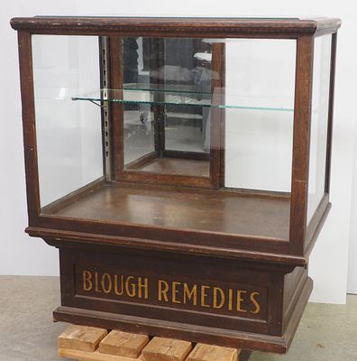 Floor model display case with glass shelf and mirrored back doors, stenciling on base for 