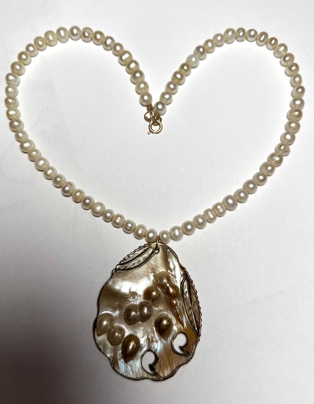 מחרוזת פנינים אובליות לבנות 7X6 מ''מ- אורך 44 ס''מ עם תליון גדול אם הפנינה - צדף טבעי עם פנינים 