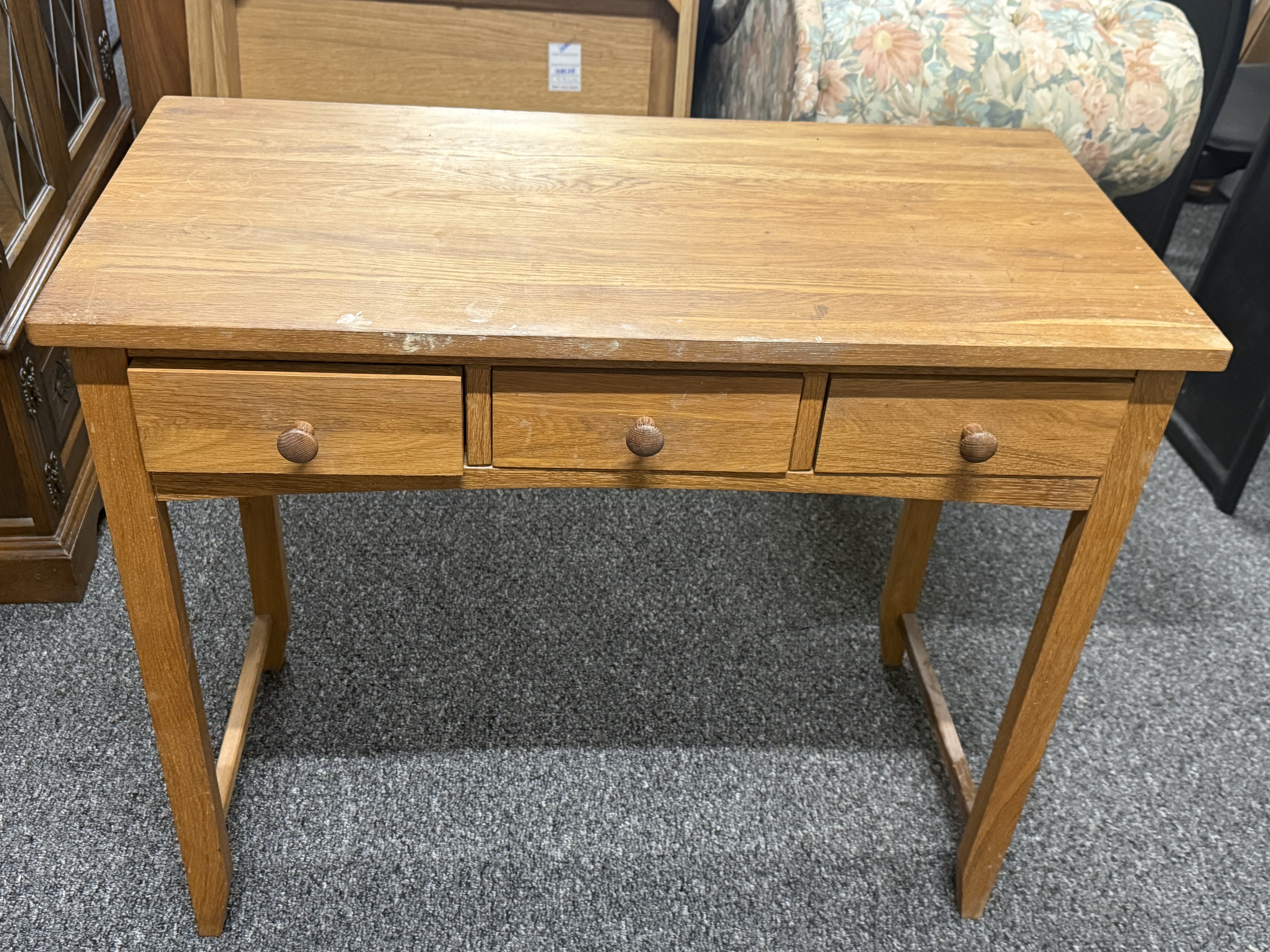 A contemporary light oak three-drawer writing desk