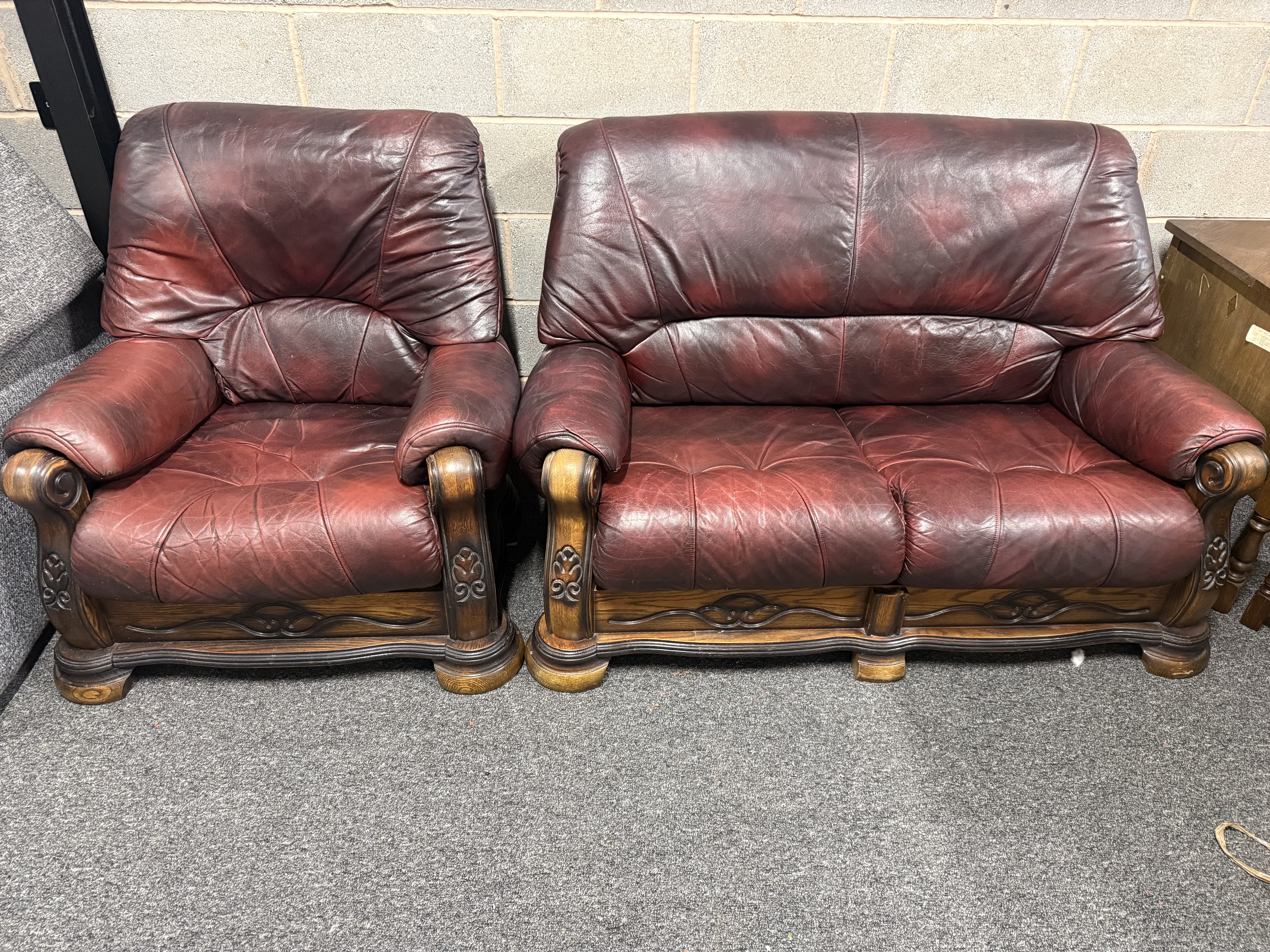 A matching oxblood leather sofa and armchair with carved frames