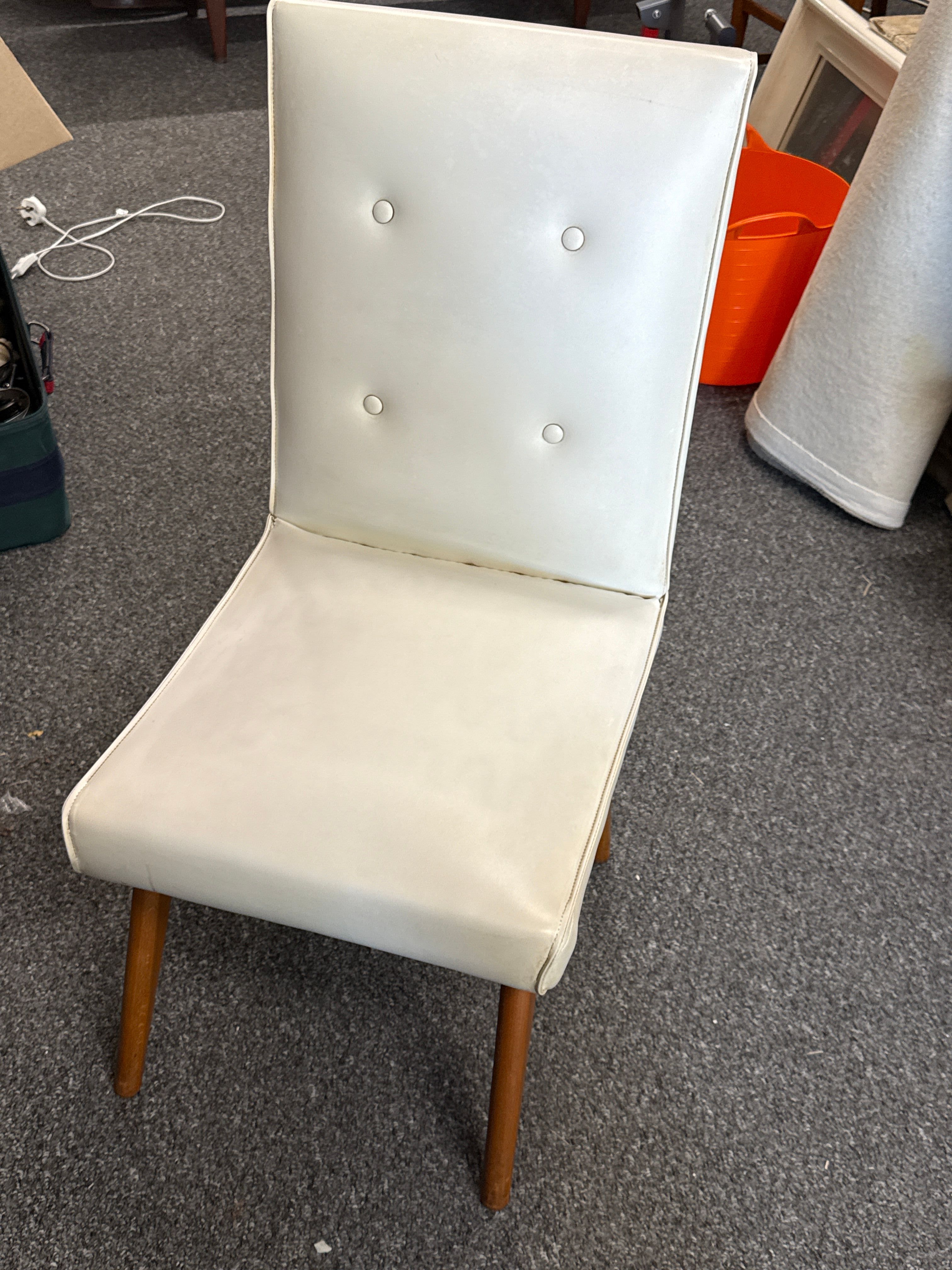 A Mid-Century Modern button-tufted cream vinyl slipper chair