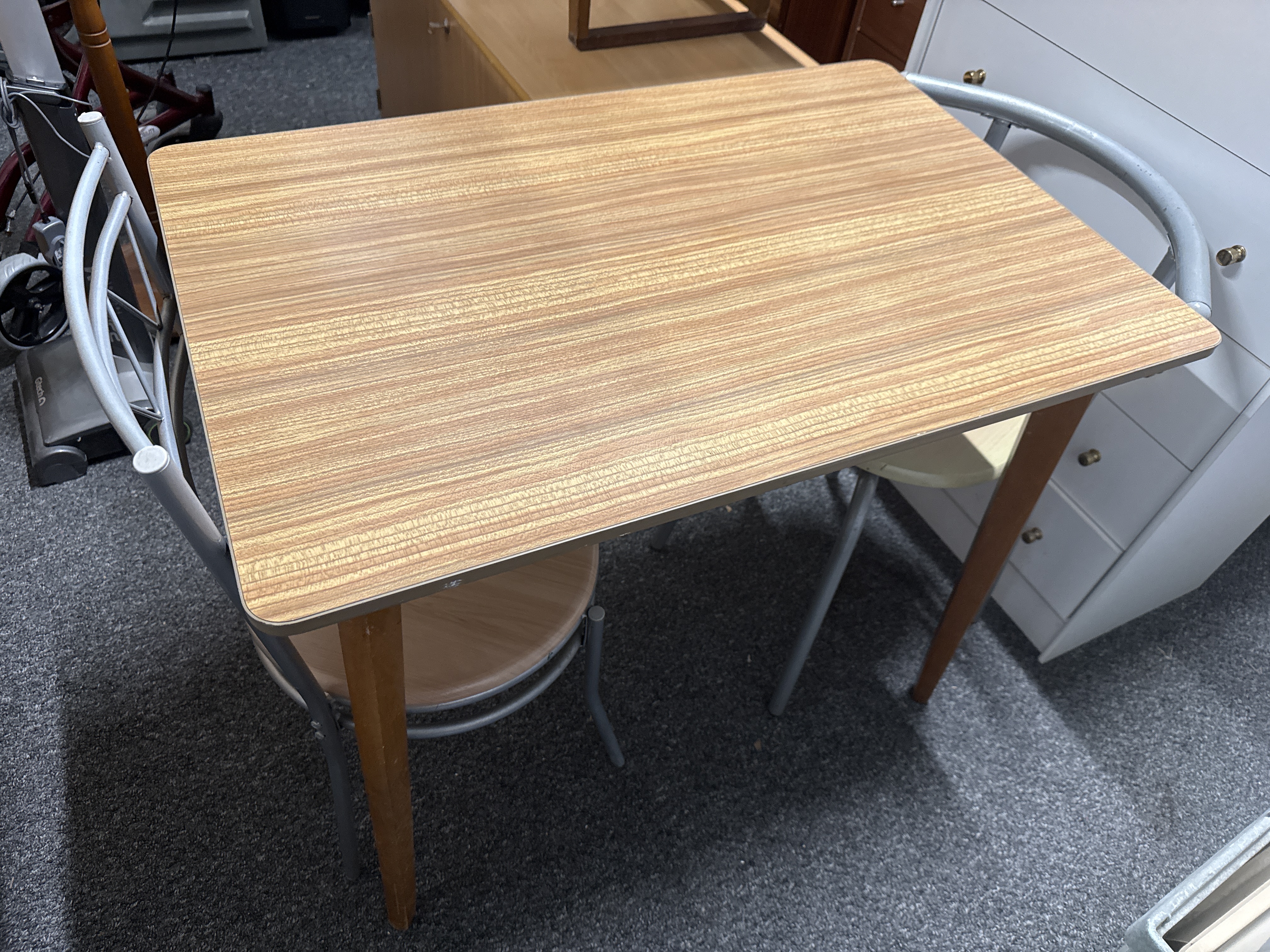A mid-century modern laminate dining table and two chairs