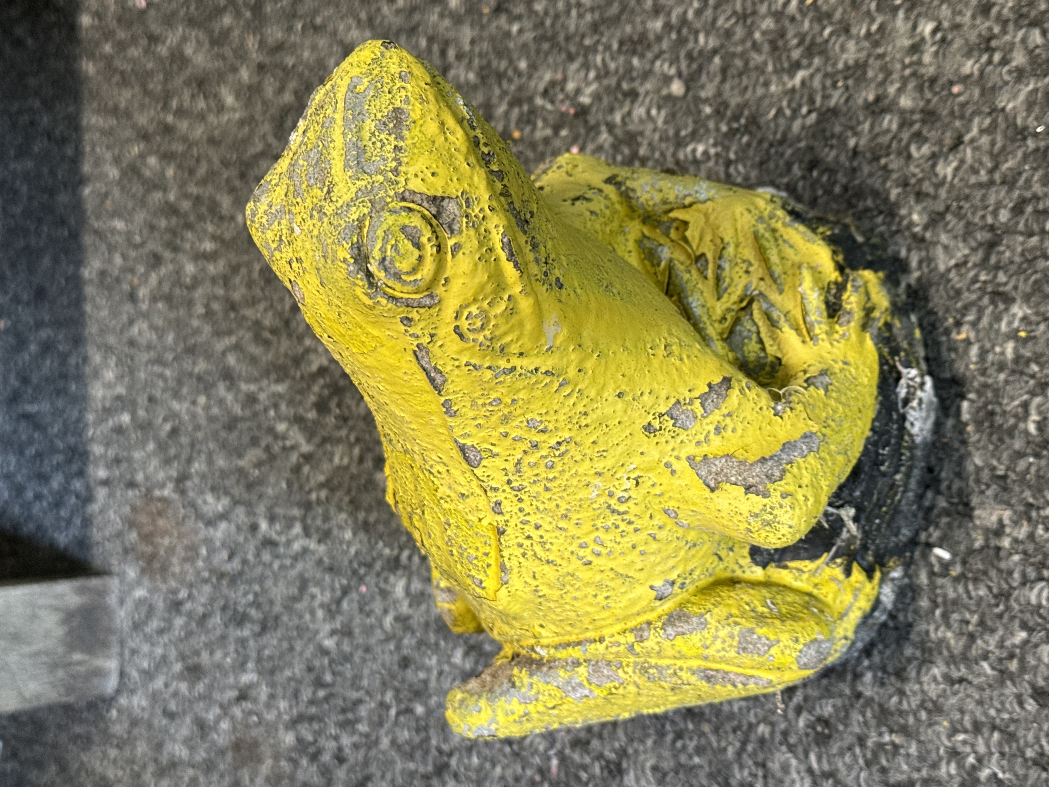 A vintage weathered concrete garden ornament of a seated frog
