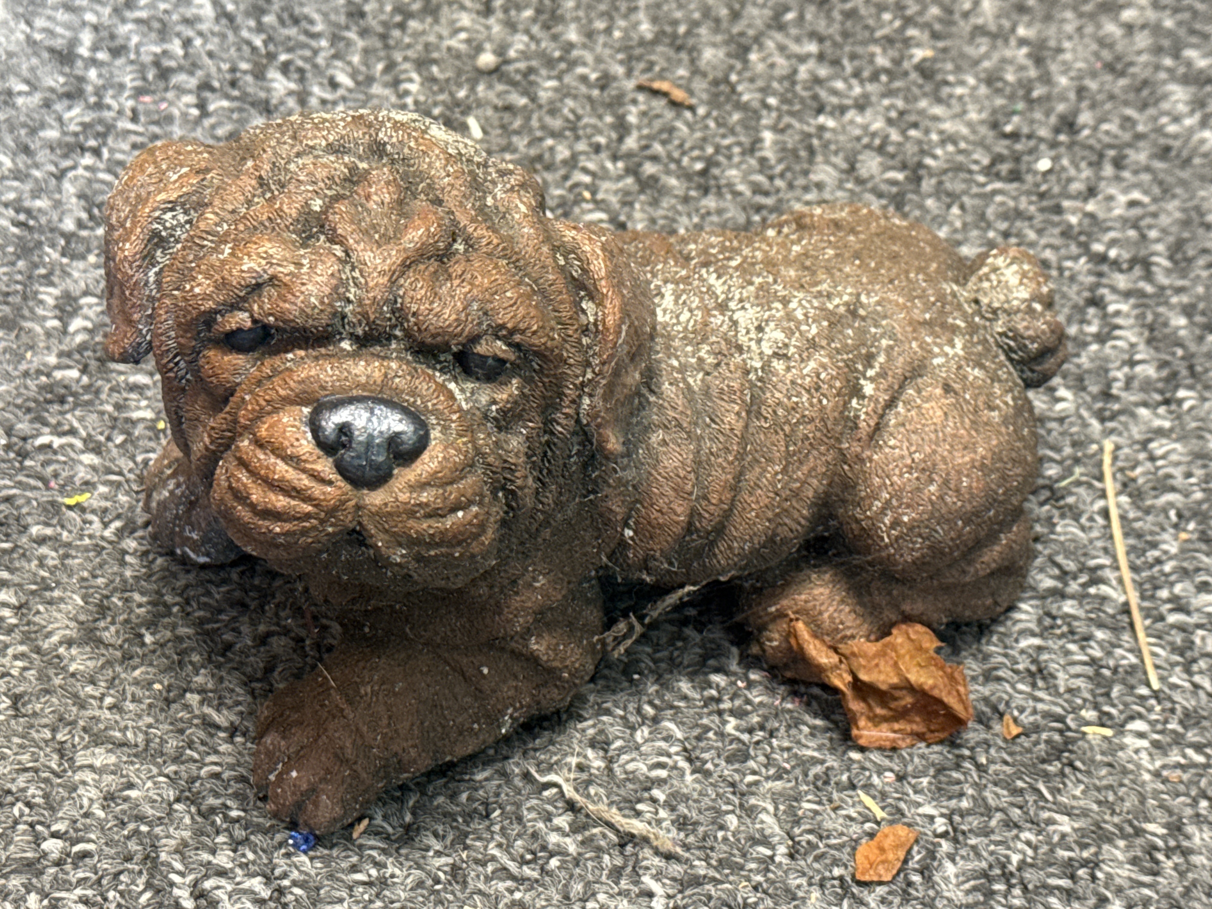 A cast stone garden ornament of a recumbent bulldog puppy