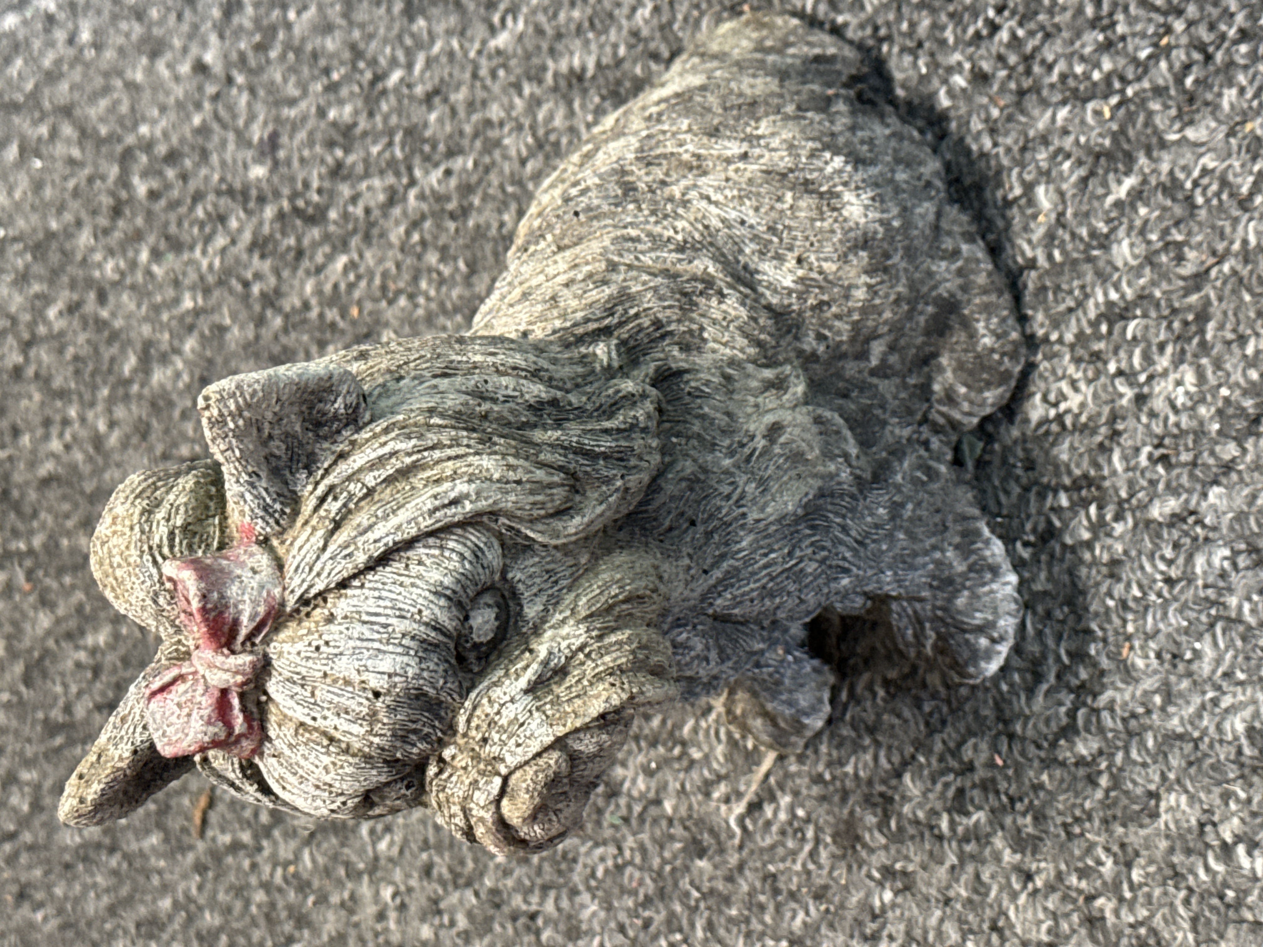 A weathered cast stone garden statue of a Yorkshire Terrier