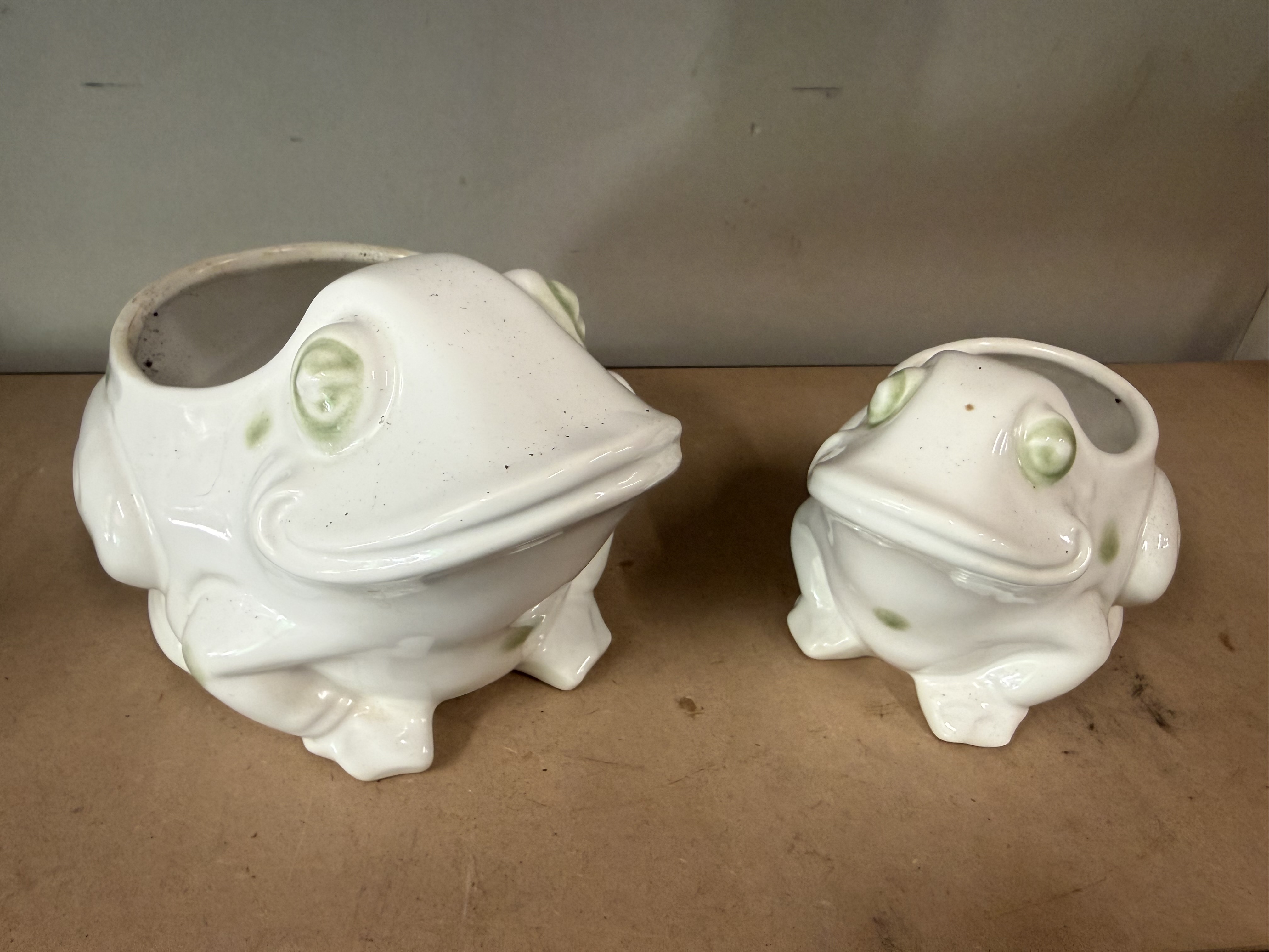 A pair of graduated white ceramic frog-shaped containers