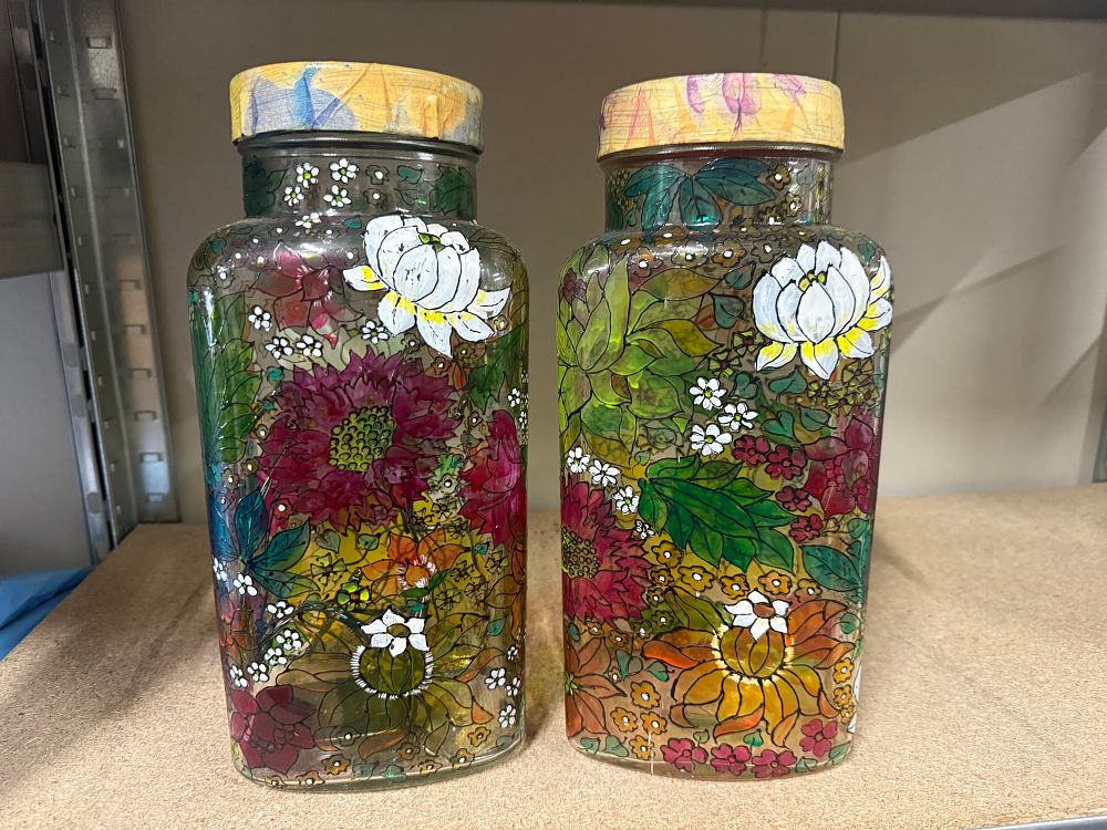 Lot 29: A pair of hand-painted clear glass jars with floral designs