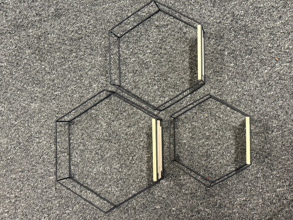 Lot 159: A trio of graduated hexagonal black metal and wood wall shelves