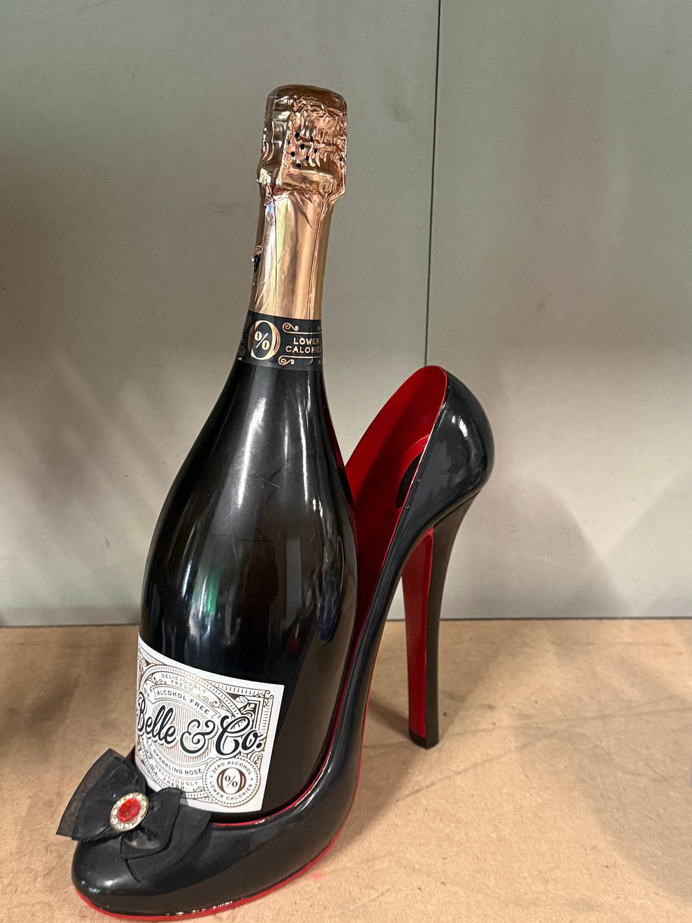 Lot 86: A bottle of Belle and Co alcohol free sparkling rosé in a shoe holder