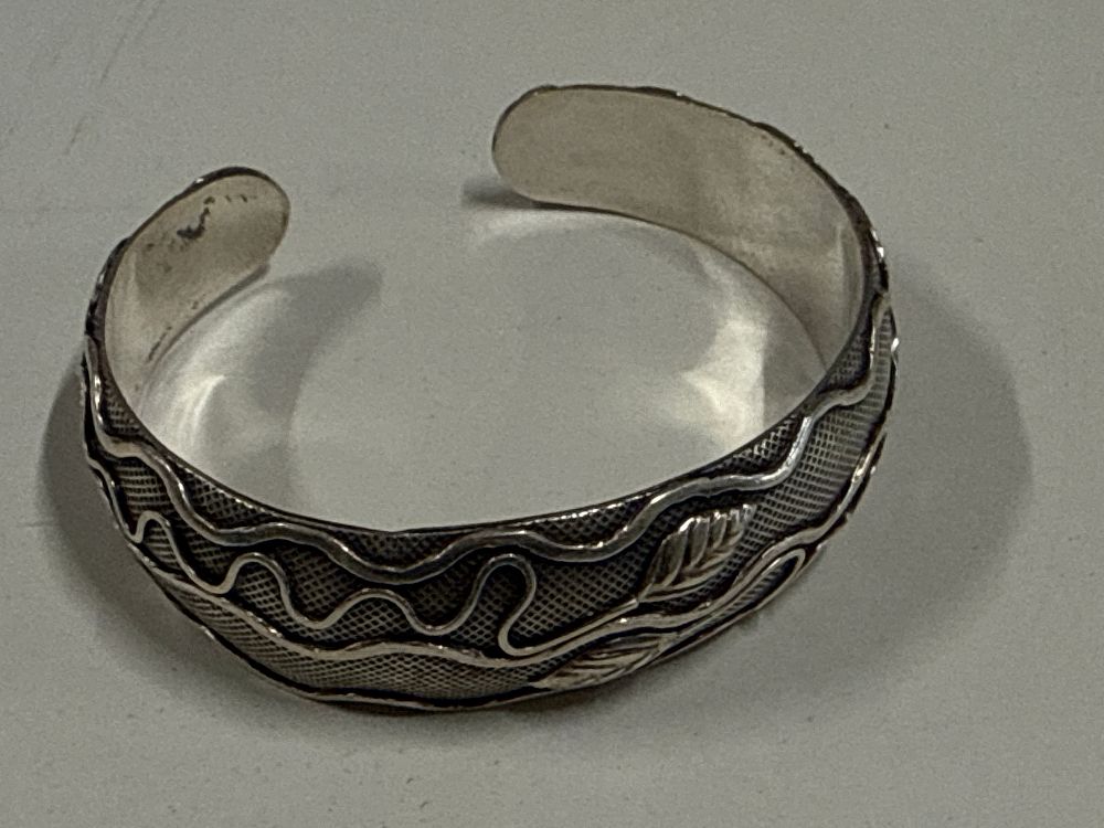 Lot 109: A wide sterling silver cuff bracelet with leaf decoration 32 Grams