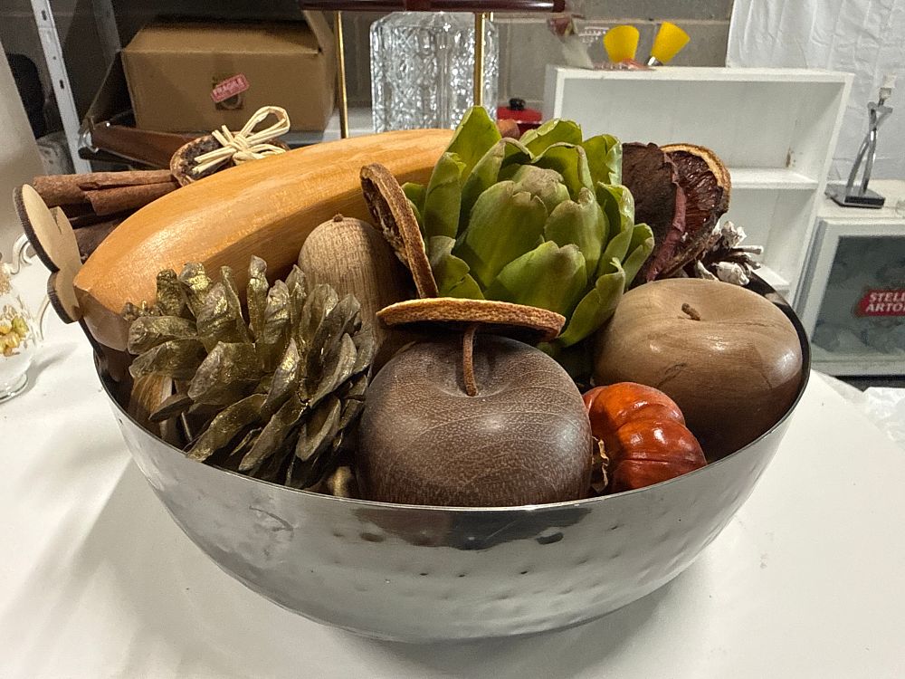 Lot 132: An assortment of decorative potpourri and turned wooden fruit in a hammered metal bowl