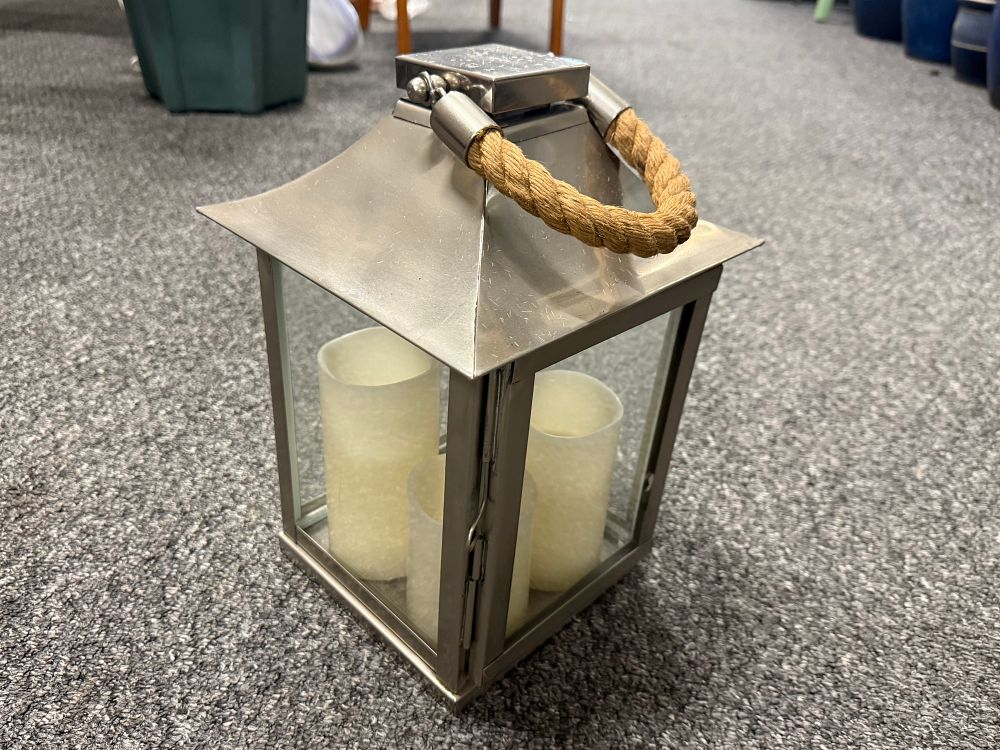 Lot 141: A contemporary stainless steel and glass lantern with LED candles