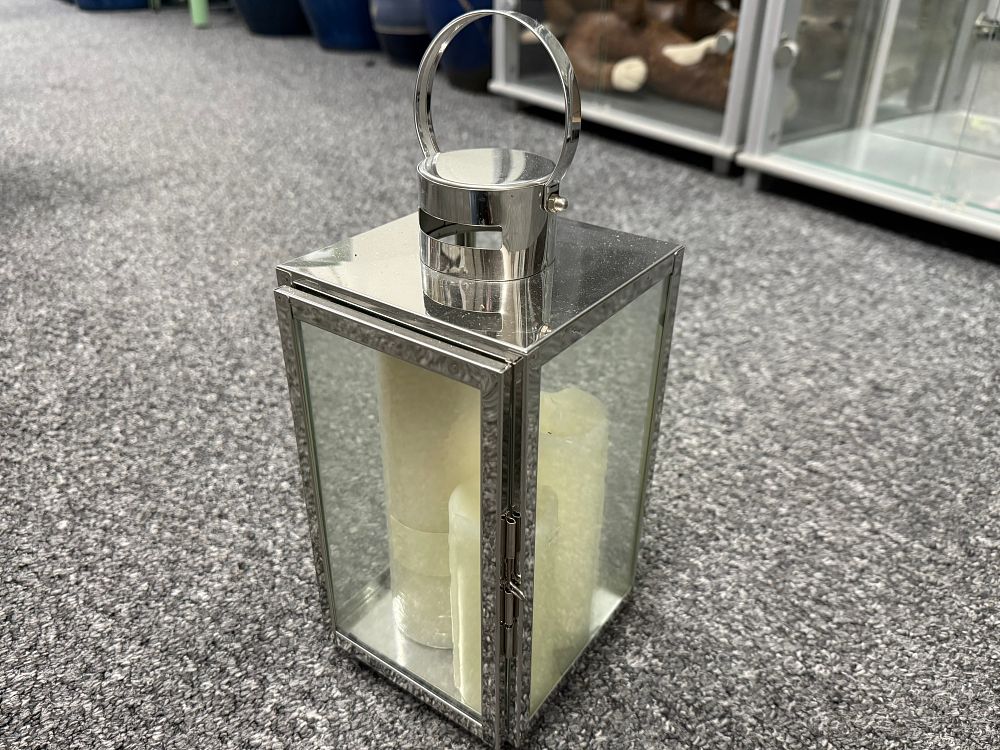 Lot 142: A contemporary silver toned metal and glass lantern with three flameless candles