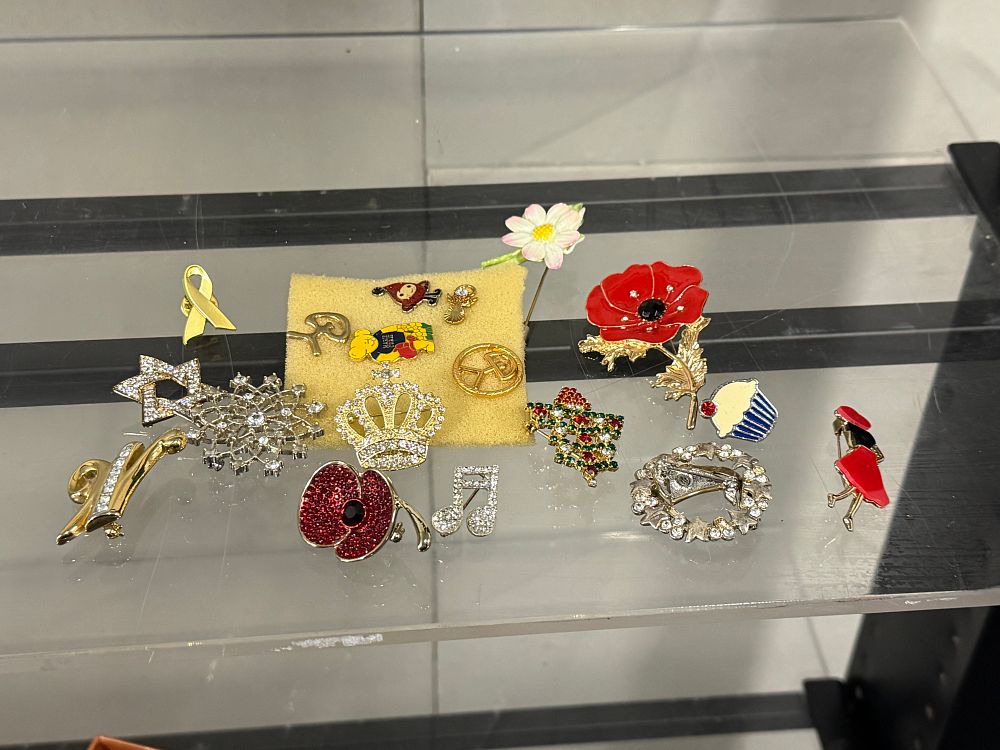 Lot 145: A collection of sixteen novelty and commemorative costume brooches and pins