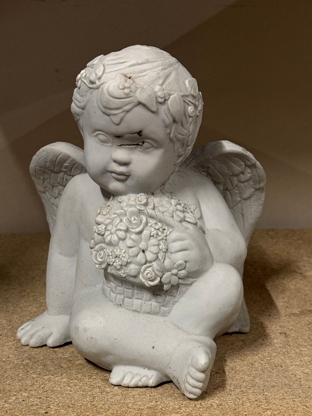 Lot 147: A cast resin evil looking cherub figurine holding a basket of flowers