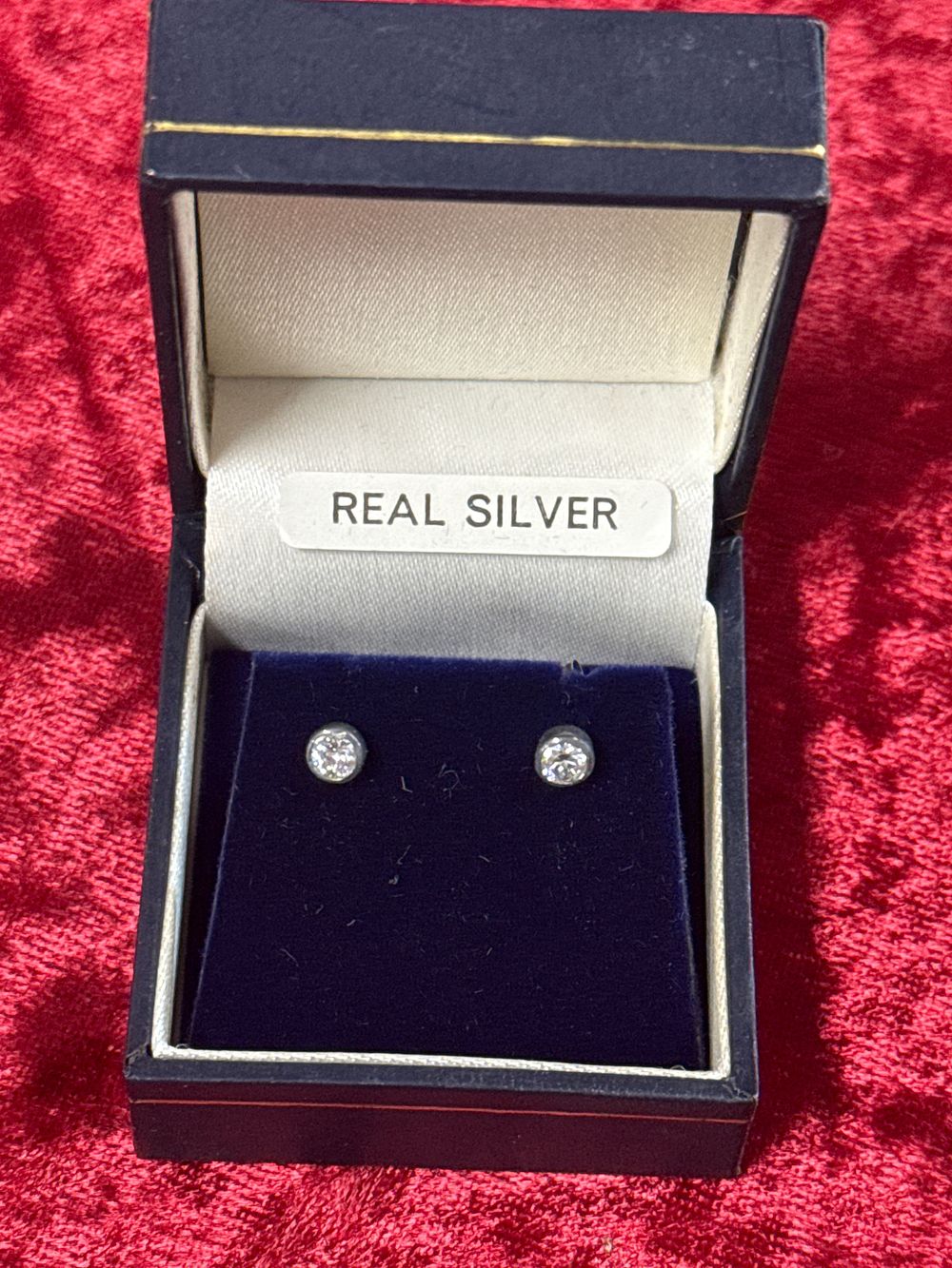 Lot 96: A pair of silver bezel-set solitaire stud earrings
