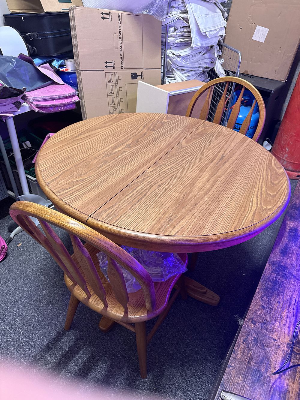 Lot 222: A circular oak drop-leaf dining table and two matching chairs