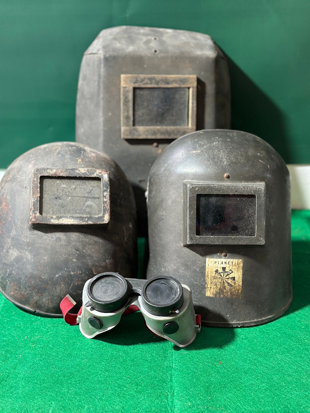 Three Vintage Industrial Welding Helmets and a Pair of Welding Goggles. This lot comprises three 