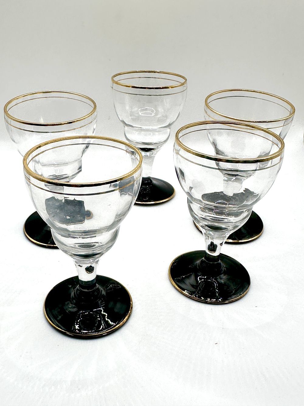 A Set of Five Mid-20th Century Clear and Black Glass Stemmed Glasses with Gold-Tone Accents. This 