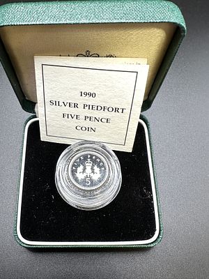 A 1990 Great Britain Royal Mint Silver Proof Piedfort Five Pence Coin. The silver-colored coin 