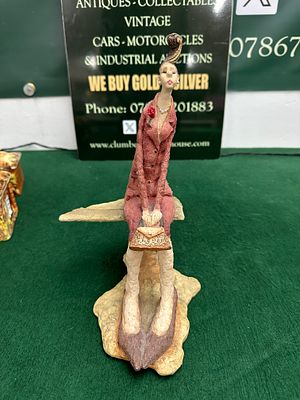 A contemporary stylised resin figurine of a seated female figure. A contemporary, stylised 