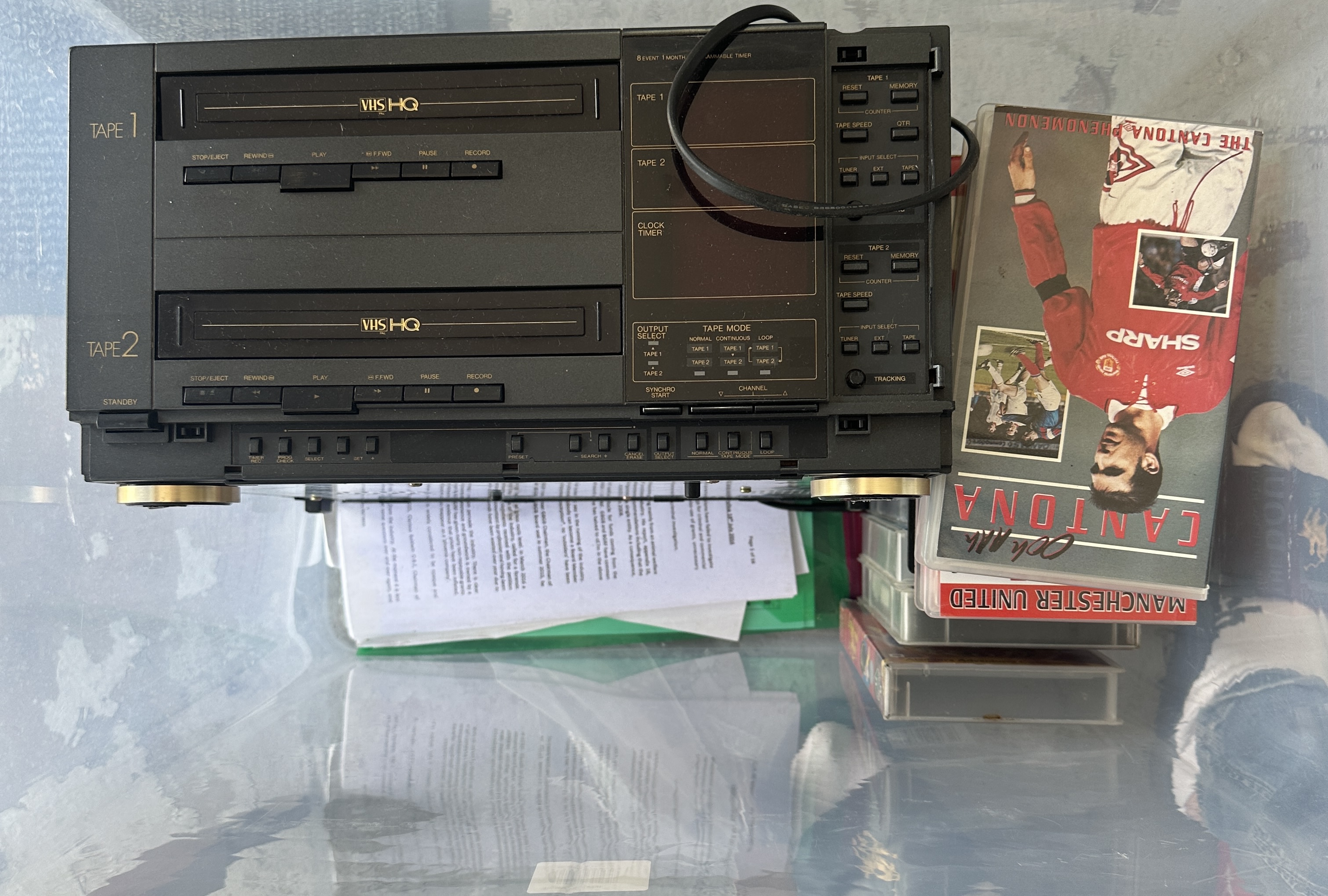 A vintage twin-deck VHS video cassette recorder and a collection of VHS tapes