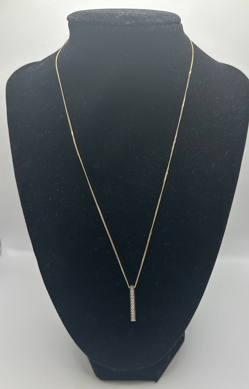 Lot 254: A 9ct yellow gold and diamond-set vertical bar pendant necklace