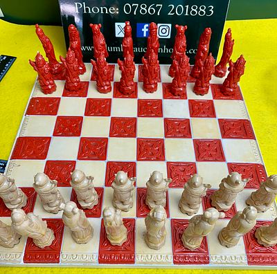 An Oriental Themed Resin Chess Set with Matching Decorative Board. A set of thirty-two chess 