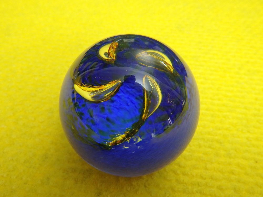 Lot 242: A spherical cobalt blue and yellow swirled studio glass paperweight