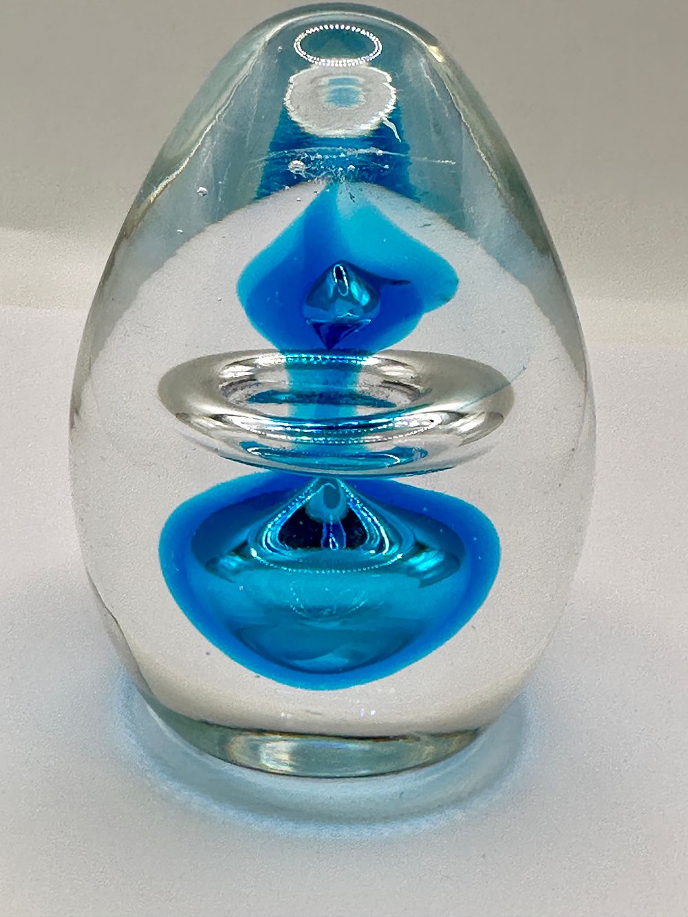 Lot 290: An Egg-Shaped Glass Paperweight with Blue and White Metal Inclusions