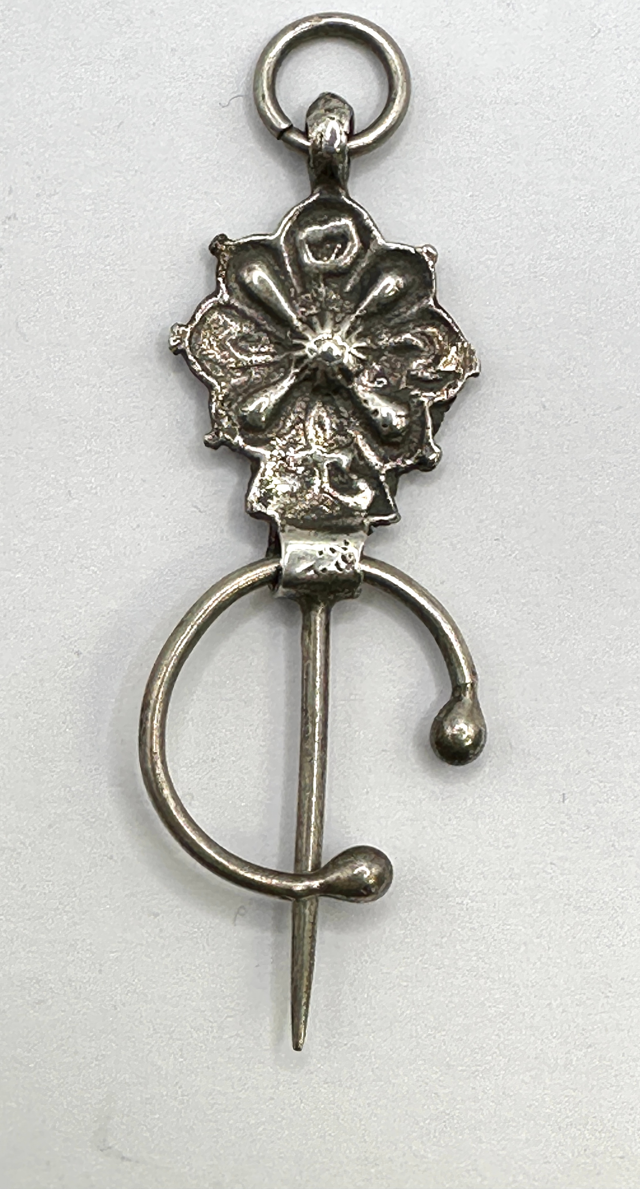 A White Metal Penannular Brooch-Pendant, Featuring A Stylised Rosette Head