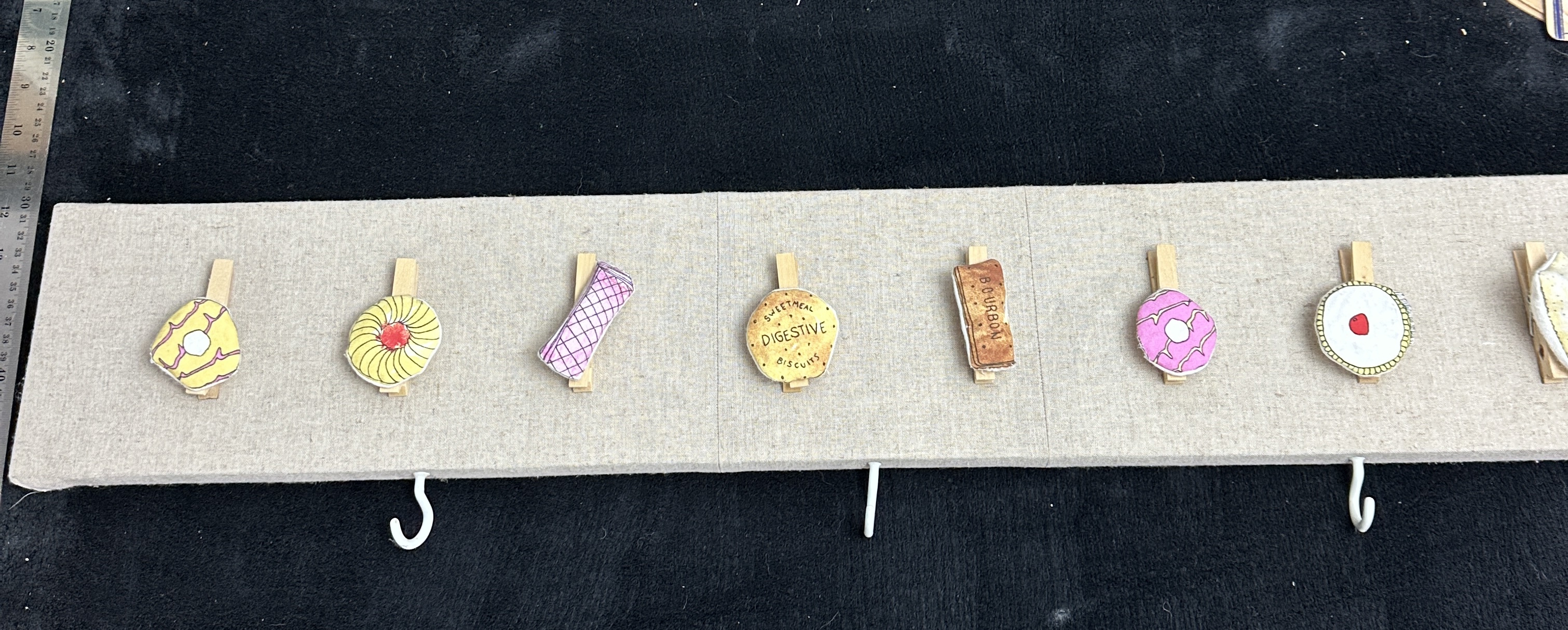 A Contemporary Fabric Upholstered Wall Board with Biscuit Themed Pegs