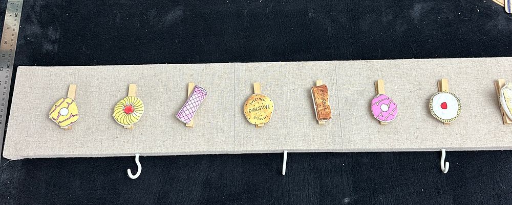 Lot 71: A Contemporary Fabric Upholstered Wall Board with Biscuit Themed Pegs