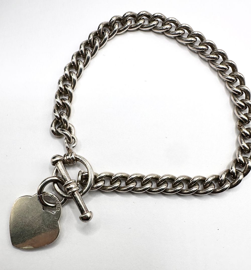 Lot 233: A 925 Silver Curb Link Bracelet with Heart Charm