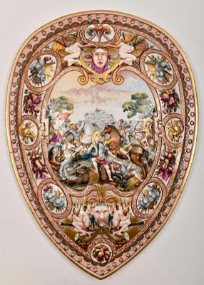 A shield. Capodimonte porcelain polychrome and gilt decoration en relief, "grotesque masks and 